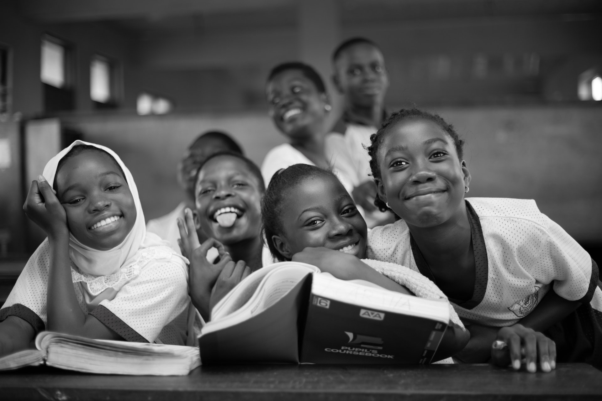 Smiling schoolchildren gathered around their coursebook