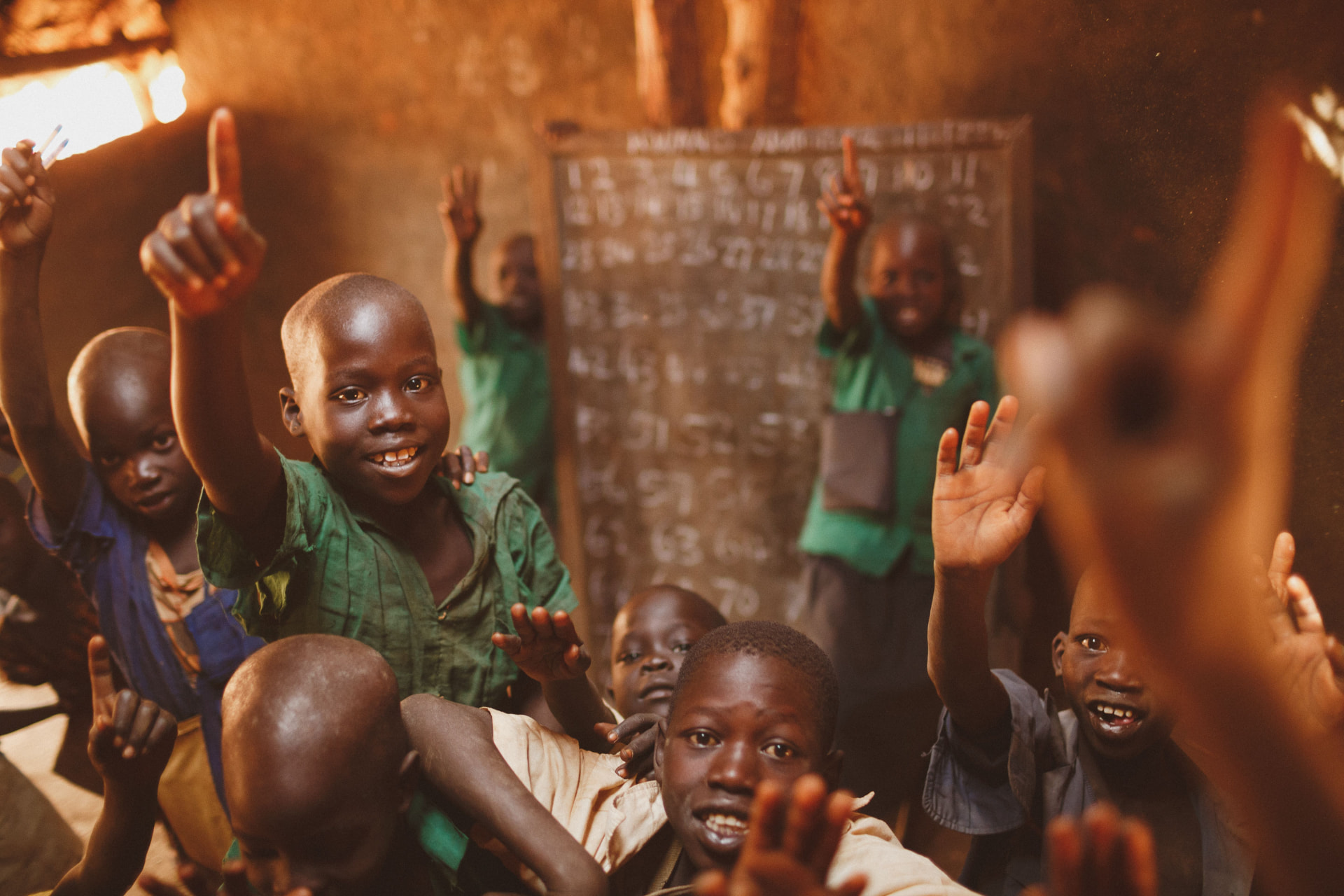 Children in a classroom raising their hands eagerly